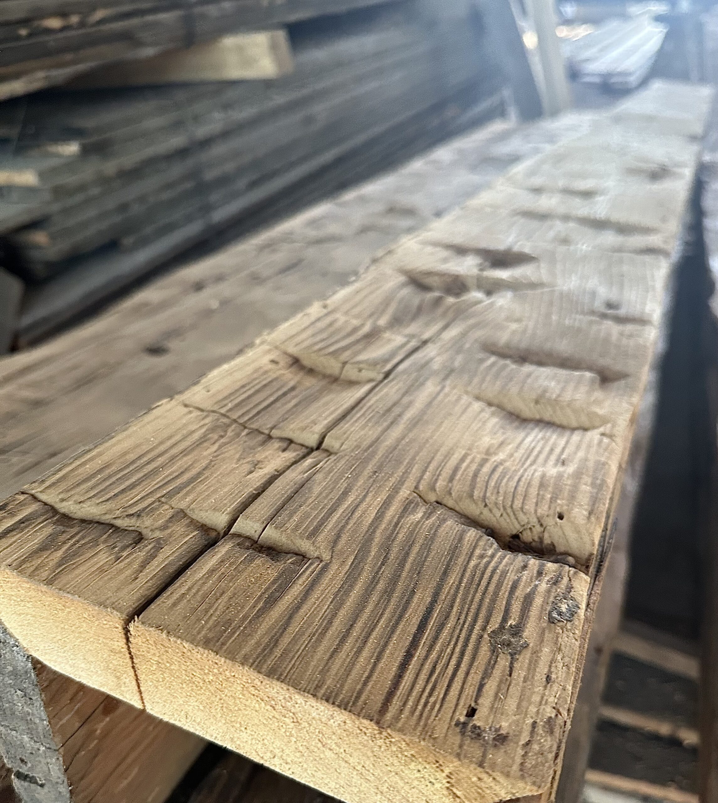 Close-up of hand-hewn reclaimed barn wood showing non-repeating axe marks and checking along the grain